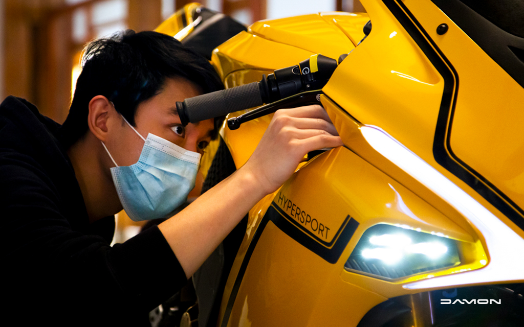 A man looking at the handlebar of a gold Damon Hypersport