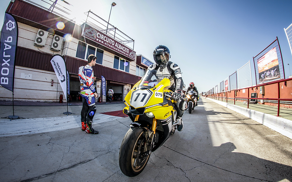 Motorcycle racer on a yellow sport bike riding on a raceway in a summer day 