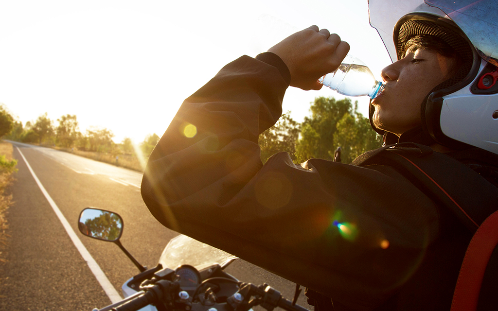 A motorcycle rider drinking a bottle of water